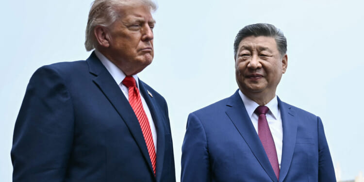 Waist-high shot of President Donald Trump and Chinese President Xi Jinping against a pale blue sky.