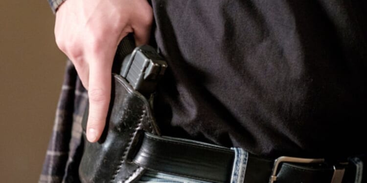 A man begins to pull a gun from his holster.