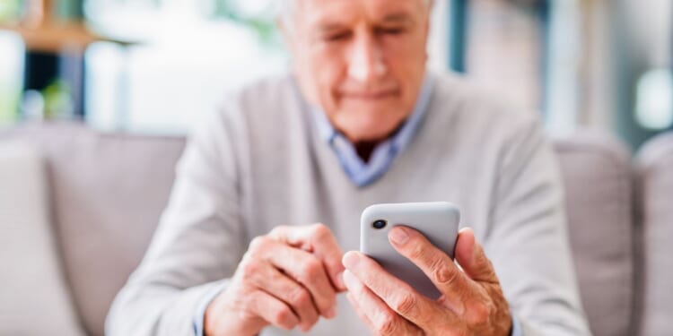 An elderly man looks at his phone.