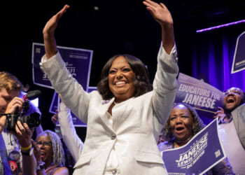 D.C. Democrat mayoral primary winner Janeese Lewis George in white pant suit waves both hands to supporters.