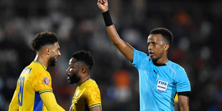 Somali FIFA referee Omar Abdulkadir Artan holds up a card during the Africa Cup of Nations Group F football match between Gabon and Ivory Coast in Marrakech on Dec. 31, 2025.