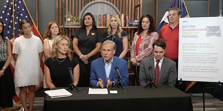 Texas Gov. Greg Abbott speaks at a table with microphones.