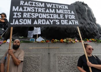 Two protesters hold a large placard blaiming the media for the death of Jason Arday Monday during a vigil in London's Trafalgar Square.