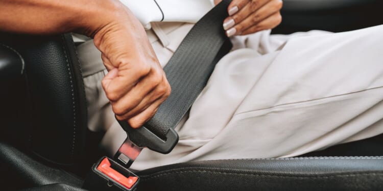 A close-up of someone putting on a seat belt.