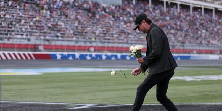 NASCAR Hall of Famer Kurt Busch lays white roses on the "8" stenciled of the infield grass during the remembrance ceremony for his brother, Kyle Busch, who passed away suddenly at the age of 41, prior to the NASCAR Cup Series Coca-Cola 600 at Charlotte Motor Speedway on May 24, 2026, in Concord, North Carolina.