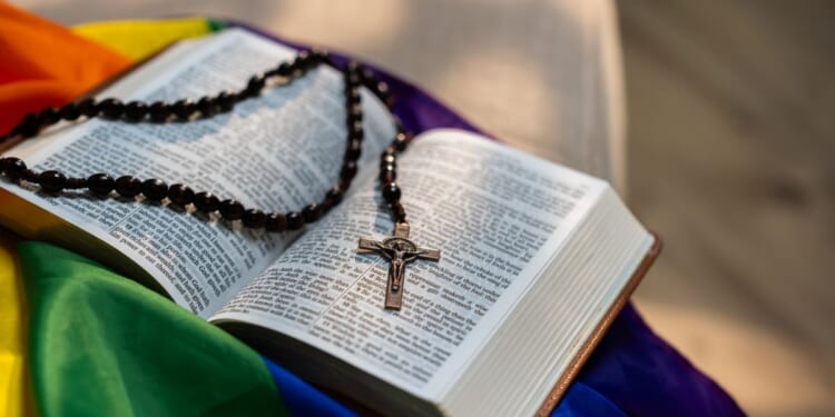 A Holy Bible sitting on top of a rainbow flag.