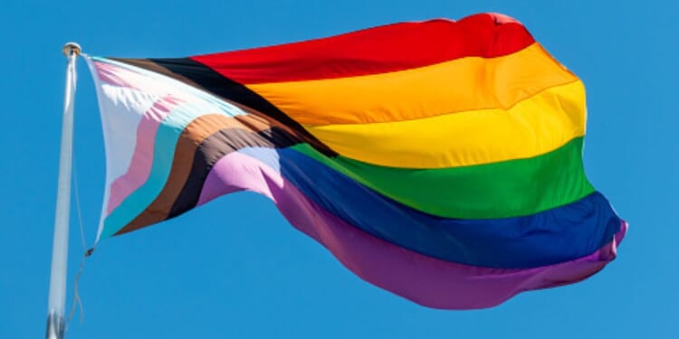 An LGBTQ flag flies in the sky.