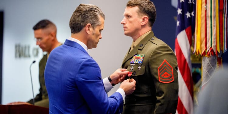 Secretary of War Pete Hegseth pins a medal on Marine Gunnery Sgt. Jonathan Eby, right, during a Pentagon event Wednesday to honor Marines who were serving during the 2021 Abbey Gate bombing in Kabul, Afghanistan.