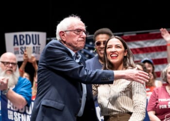 Sen. Bernie Sanders greets Rep. Alexandria Ocasio-Cortez at The People v. The Powerful rally at the Detroit Opera House on July 18, 2026, in Detroit, Michigan.