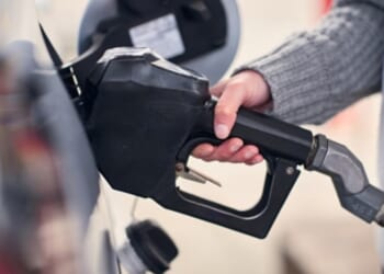 A woman grabs gas pump at a gas station.