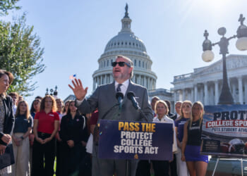 Sen. Ted Cruz speaks at a podium reading Pass the Protect College Sports Act outside the U.S. Capitol, surrounded by supporters, with a sign reading Protect College Sports Act to the right.
