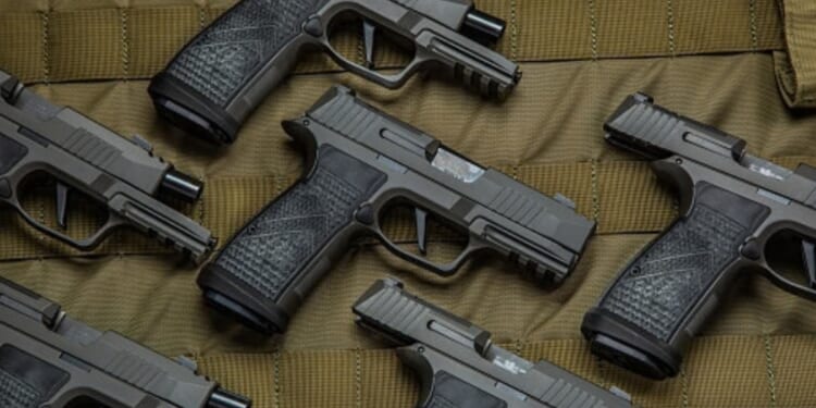Pistols are laid out on a brown fabric in a pattern.