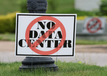 A sign on grass reads "NO DATA CENTER" with a red circle and slash, indicating opposition to a data center.