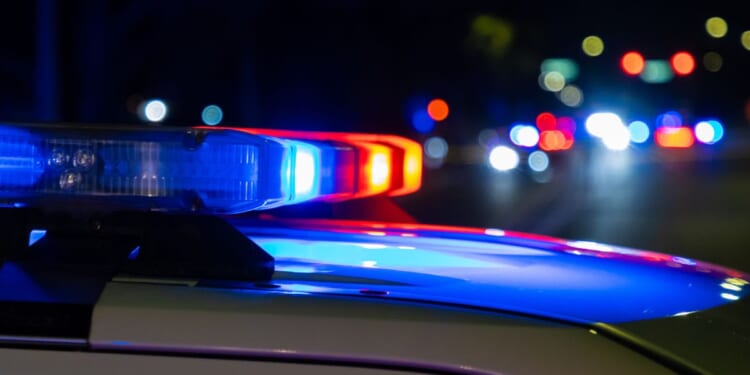A crime scene in a city at night with blue and red police lights.