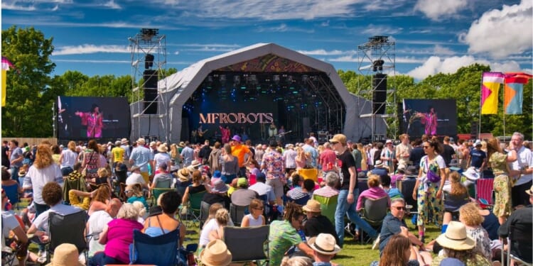 A large crowd in front of a stage at an outdoor summer music festival in England.