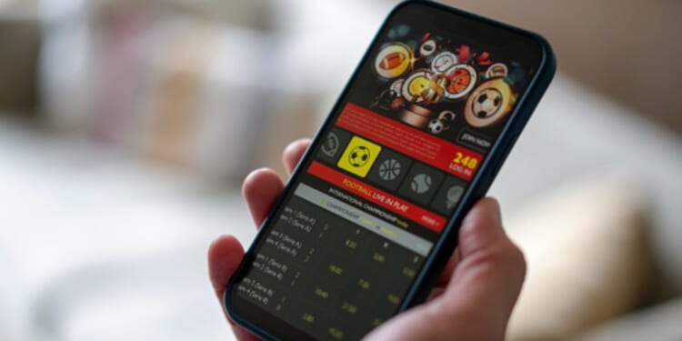 A phone screen is displayed with a gambling app on the interface.