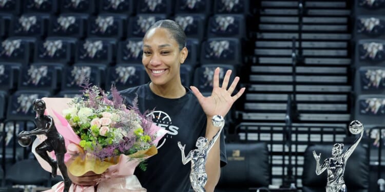 A'ja Wilson of the Las Vegas Aces poses while holding a bouquet of flowers after receiving the 2026 WNBA MVP award, her third consecutive and fifth career trophy, after a team walkthrough at Michelob ULTRA Arena on Oct. 8, 2026, in Las Vegas, Nevada.
