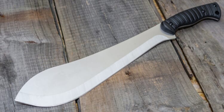 A machete is pictured on a wooden table.