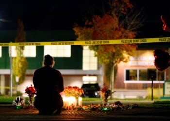 A woman grieves at a candlelight memorial out front of Silver Rail Elementary School on Oct. 15, 2026, in Bend, Oregon.