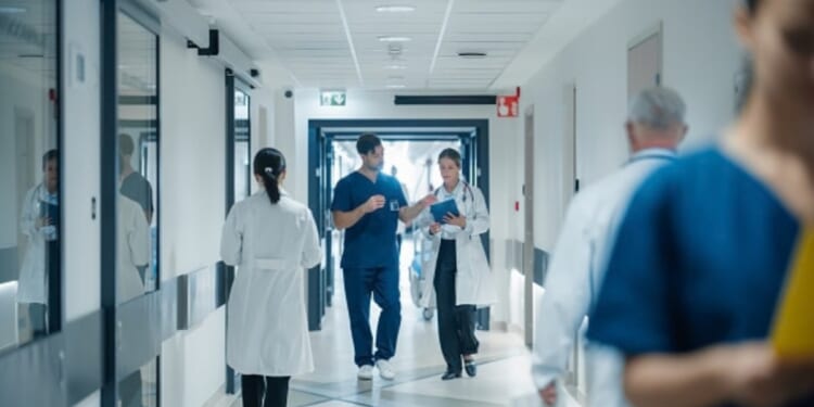 A hospital hallway is pictured as people walk through it.