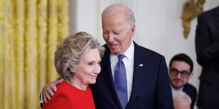 Former Secretary of State Hillary Clinton greets President Joe Biden before being awarded the Presidential Medal of Freedom in the East Room of the White House on Jan. 4, 2025, in Washington, D.C.