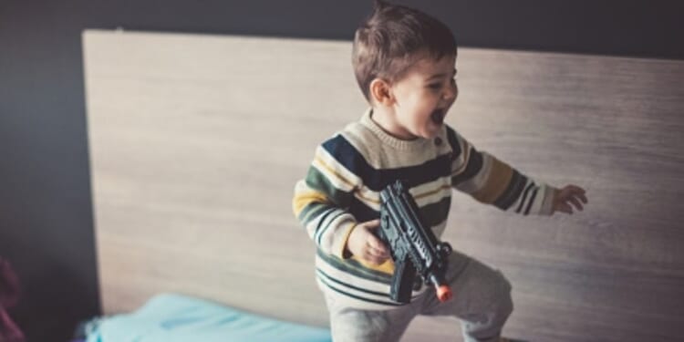 A kid plays with a BB gun.