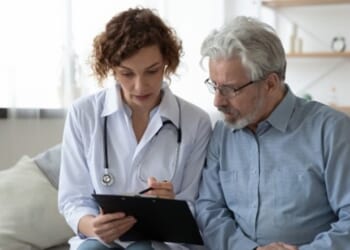 A doctor going over information on a clipboard with their patient.