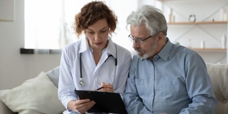 A doctor going over information on a clipboard with their patient.