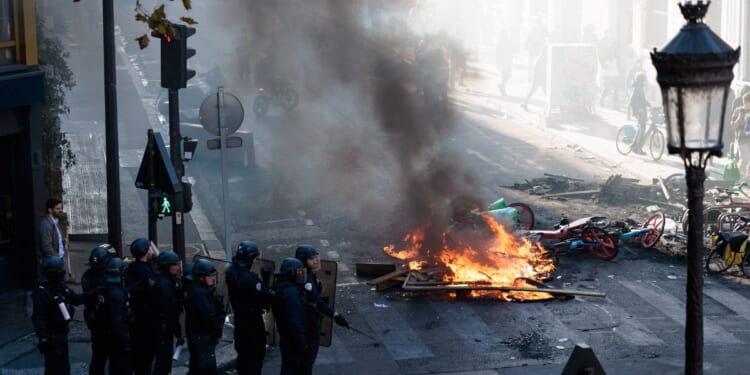 Police officers stand near a fire during an unauthorized demonstration marked by riots and clashes with law enforcement at Place de la Republique in Paris, Ile-de-France, France, on Oct. 18, 2026.