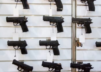 A gun rack is viewed on a wall.