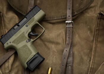 A pistol lays on a dark brown fabric.