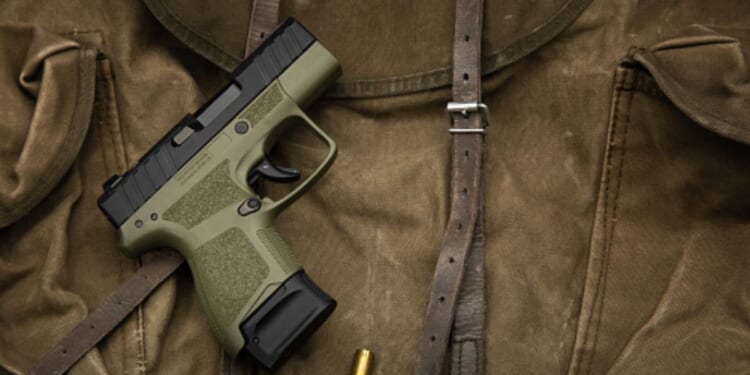 A pistol lays on a dark brown fabric.