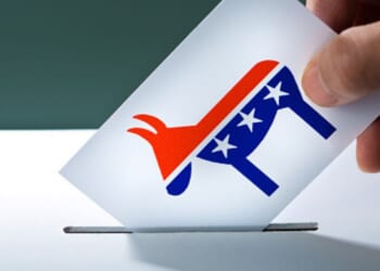 A person puts a ballot with a Democratic donkey symbol into a ballot box.