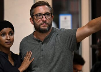Rep. Ilhan Omar stands with her husband, Tim Mynett, as they listen to Wisconsin gubernatorial candidate Francesca Hong during a campaign rally on Aug. 2, 2026, in Milwaukee, Wisconsin.
