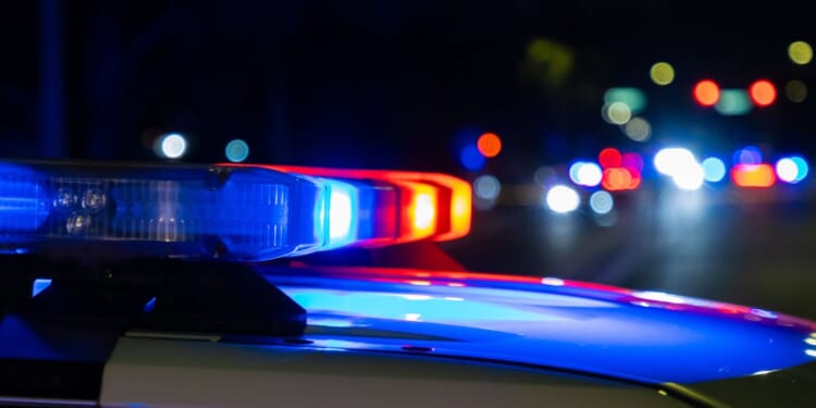 A crime scene in a city at night with blue and red police lights.